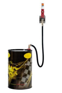 A decorated oil drum connected to a tall, red fluid pump dispenser against a white background.