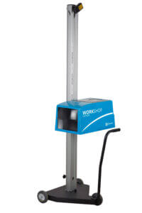 A vertical measurement device with a blue box labeled "WORKSHOP" mounted on a metal pillar, standing on a wheeled base.