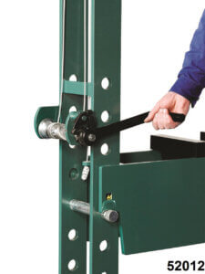 A person's arm leverages a black handle attached to a vertical green racking system with numbered label "52012."