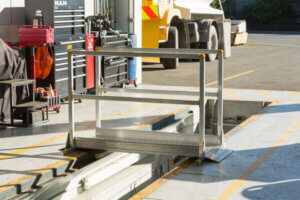 Metal passenger stairs are stationary on tarmac near airport service vehicles, suggesting boarding or disembarking activities at an airport gate.