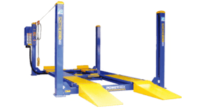 A blue and yellow four-post vehicle lift stands idle, designed to raise cars for maintenance in a garage setting.