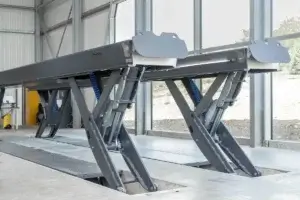 A large industrial lift system, stationary within a warehouse setting, designed for heavy-duty lifting or loading tasks.