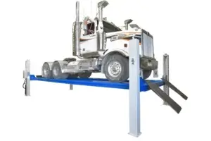 A semi-truck raised on a blue vehicle lift in a maintenance or inspection facility with a white background.
